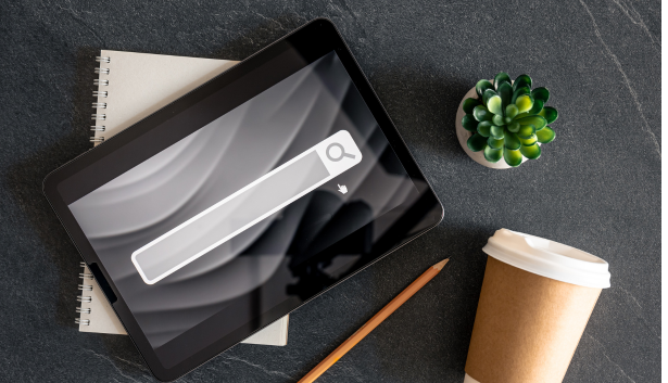 Tablet con un buscador web sobre un cuaderno y al lado de un cafe en Agencia de SEO en Badajoz