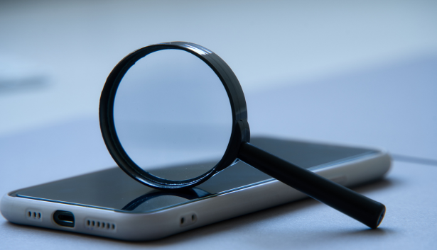 Lupa negra apoyada sobre la pantalla de un smartphone, representando la búsqueda y análisis en dispositivos móviles. Concepto relacionado con Agencia de SEO en Córdoba.