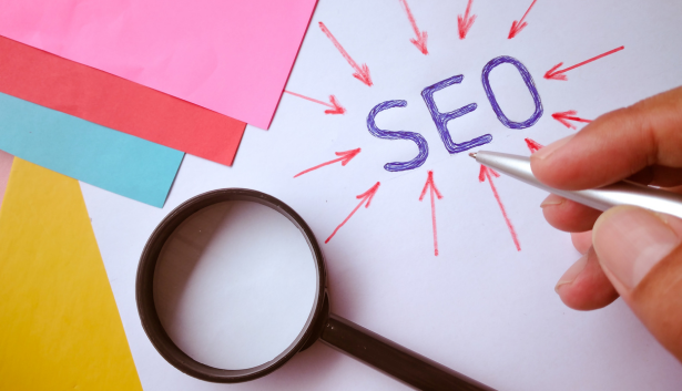 Lupa encima de una hoja la cual esta escrita SEO en Agencia de SEO en Gijón