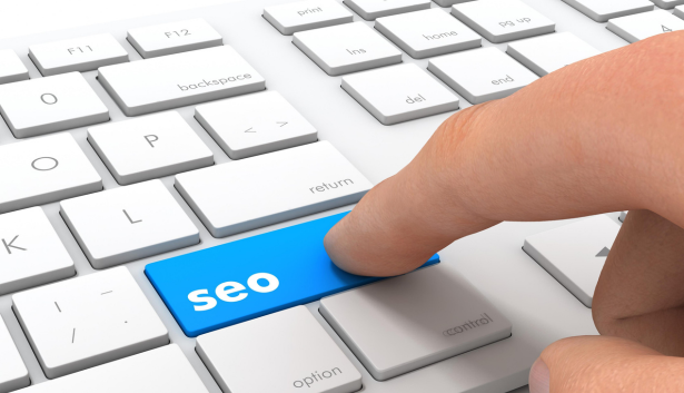 Dedo presionando una tecla azul con la palabra 'SEO' en un teclado blanco, simbolizando la optimización para motores de búsqueda. Concepto relacionado con Agencia de SEO en Leganés