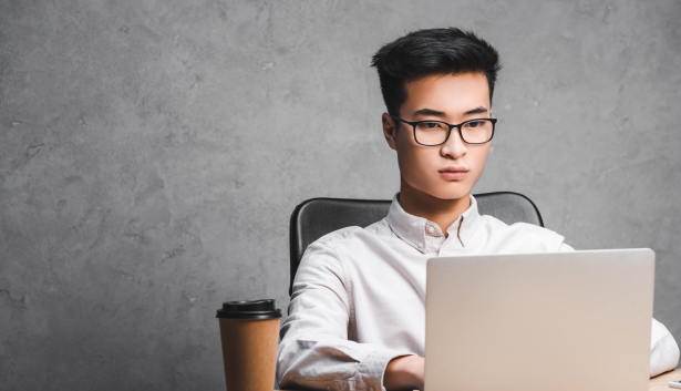 Asiático con un café al lado viendo una laptop en Agencia de SEO en Mataró