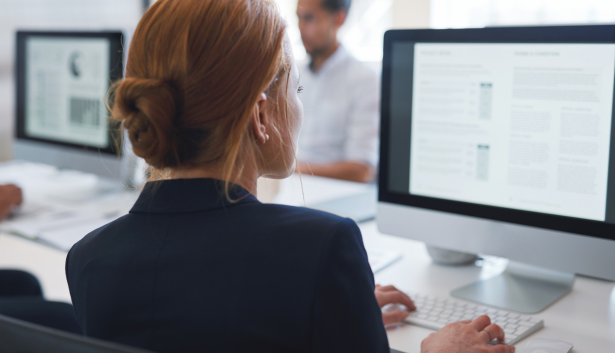 Mujer de pelo naranja mirando una PC MAC en Agencia de SEO en Oviedo​