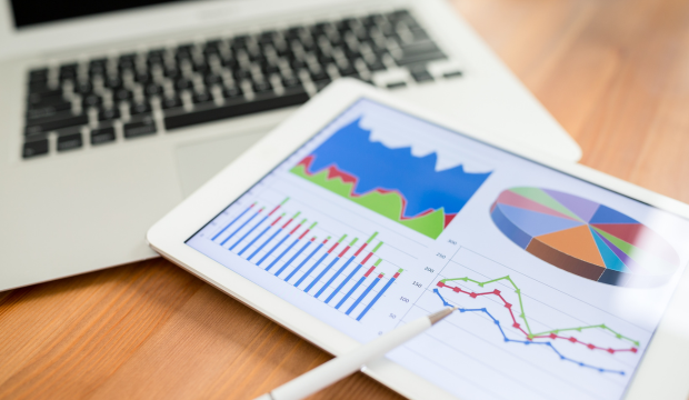 Tablet con gráficos de análisis de datos y métricas de rendimiento, junto a un ordenador portátil, representando estrategias de posicionamiento web de una agencia de SEO en Sevilla.