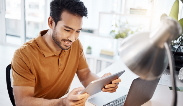 Joven profesional sonriente trabajando con una tablet en un entorno moderno, simbolizando el éxito y la eficiencia en la optimización web de una agencia de SEO en Sevilla.