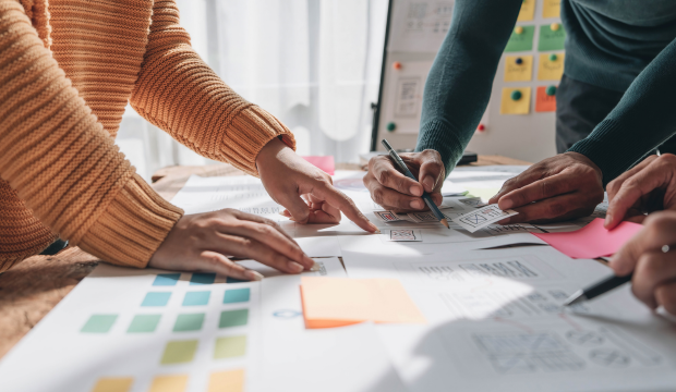 Equipo de trabajo analizando wireframes y esquemas de diseño en una mesa con luz natural, reflejando la planificación estratégica de una agencia de SEO en Terrassa.