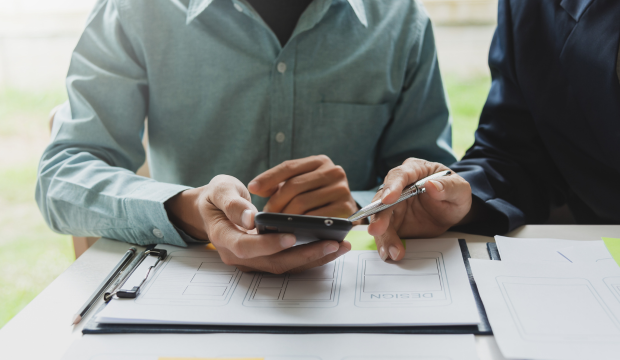 Dos profesionales analizando bocetos y estrategias de diseño en un smartphone, representando el proceso de optimización web y experiencia de usuario en una agencia de SEO en Valladolid.