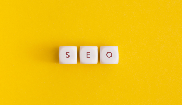 Tres bloques blancos con las letras ‘SEO’ en rojo, colocados sobre un fondo amarillo vibrante, representando la optimización web y estrategias digitales de una agencia de SEO en Vitoria-Gasteiz.