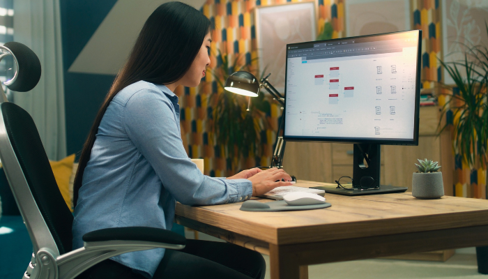 Profesional trabajando en diagramas de procesos frente a un monitor