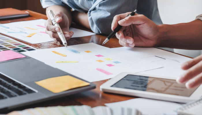 Equipo planificando el diseño de una interfaz con diagramas y dispositivos móviles