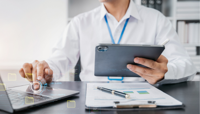 Profesional consultando una tableta y un portátil para un proyecto de desarrollo web.